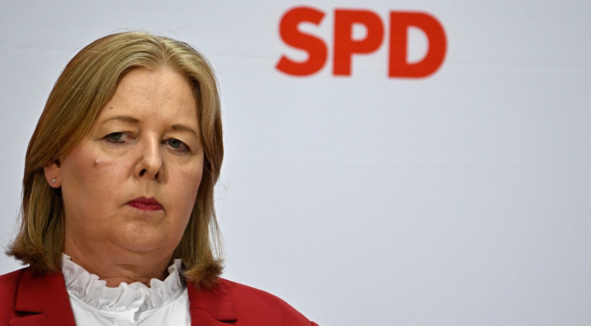 Barbel Bas seen in a red coat and white frock stands in front of SPD letters.