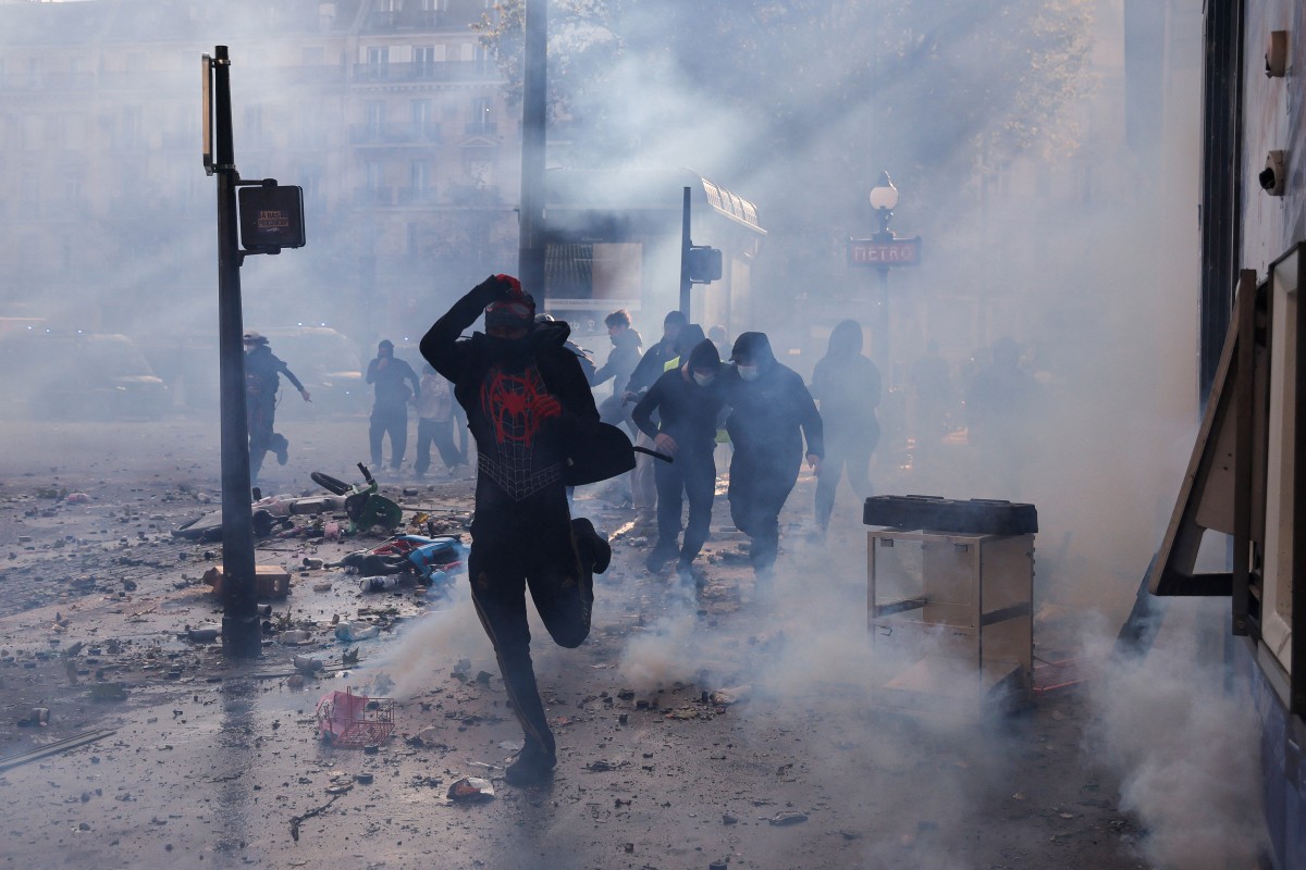 A protester runs during a demonstration against the "high cost of living", in Paris 