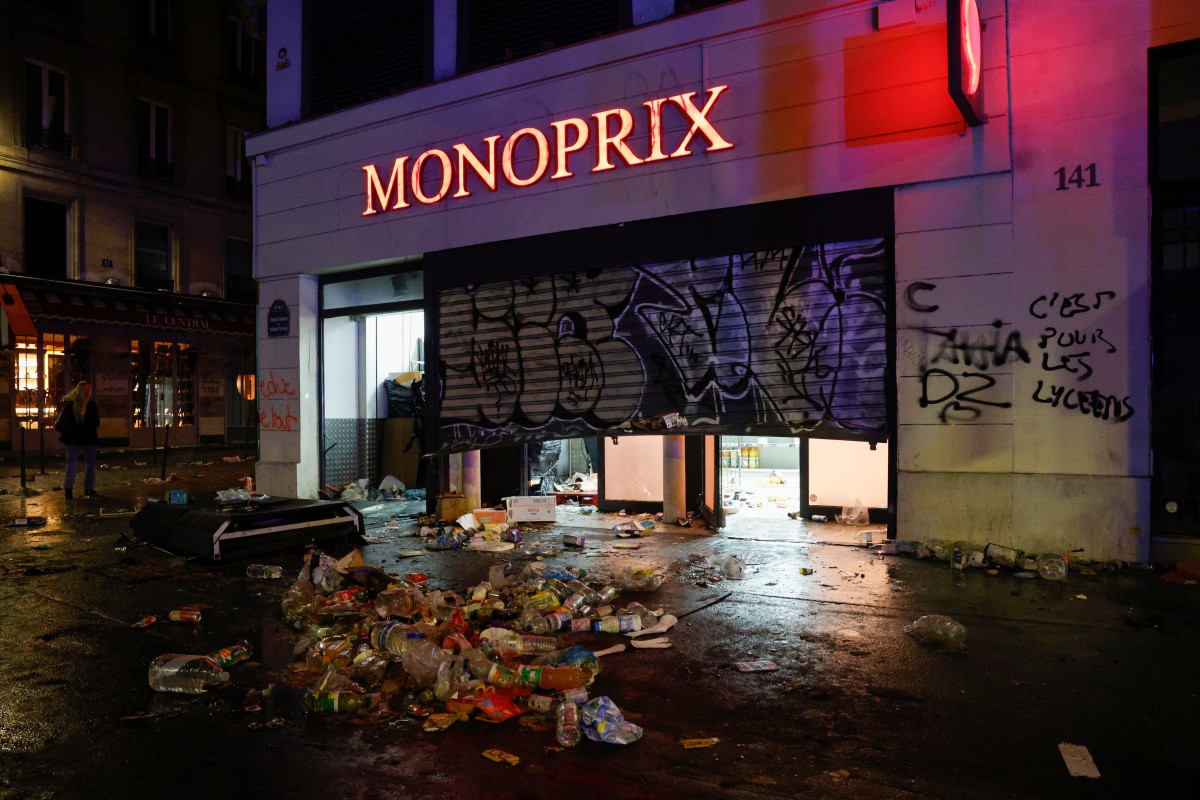 A graffiti reading "It's for the high school students" is seen on a wall of a damaged Monoprix grocery store during a demonstration to protest against the "high cost of living", in Paris